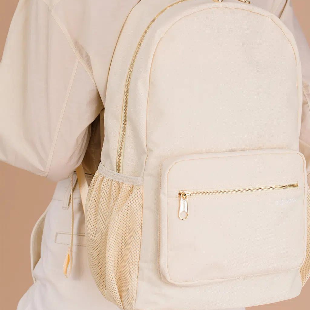 Beige neutral backpack worn by person, invented by a woman, featuring patented zip pouches on straps. Ideal for all, including non-backpack people.