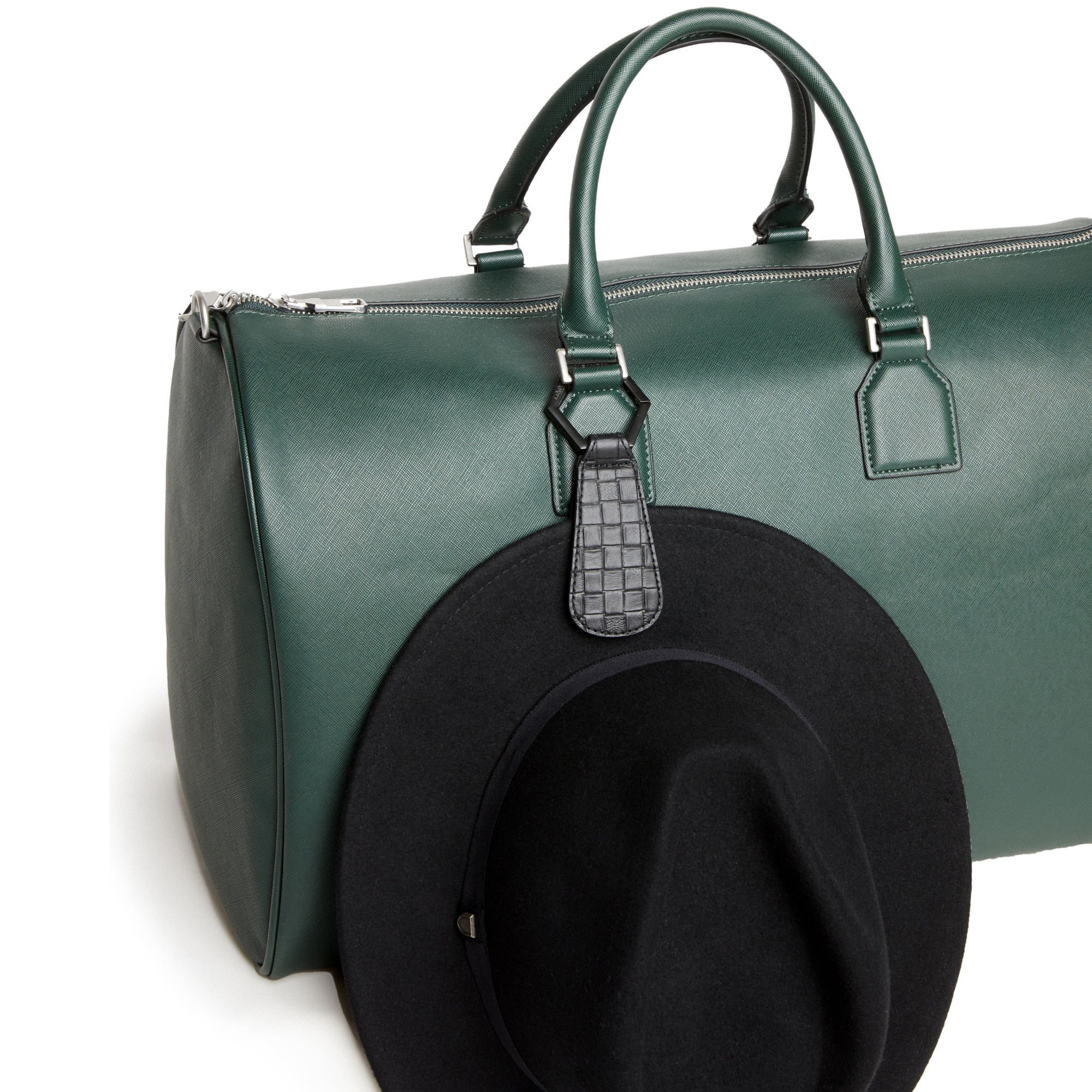 Black hat attached to a green travel bag using a TOPTOTE hat holder clip.