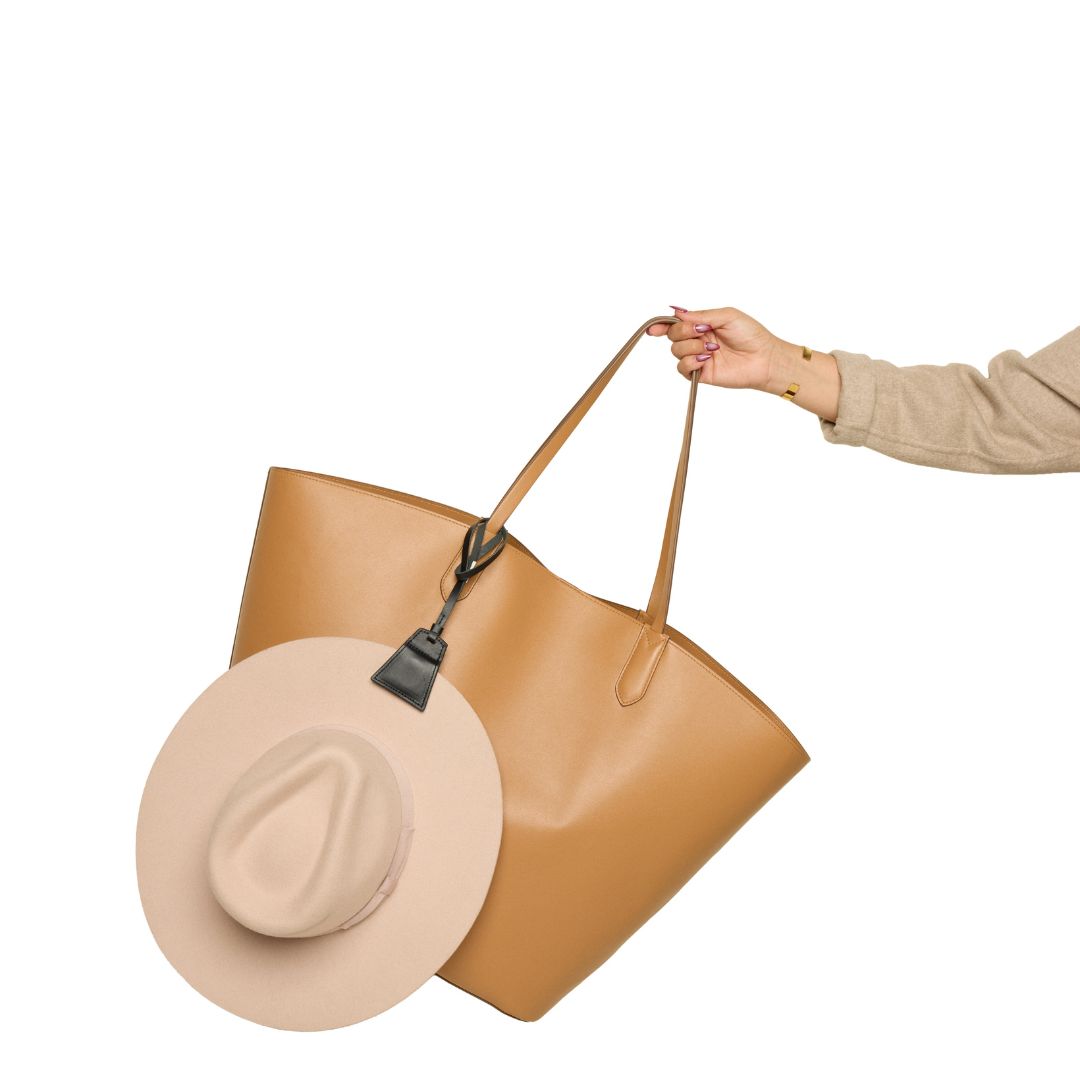 Black Lasso TOPTOTE hat clip holding a beige hat and attached to a tan tote.