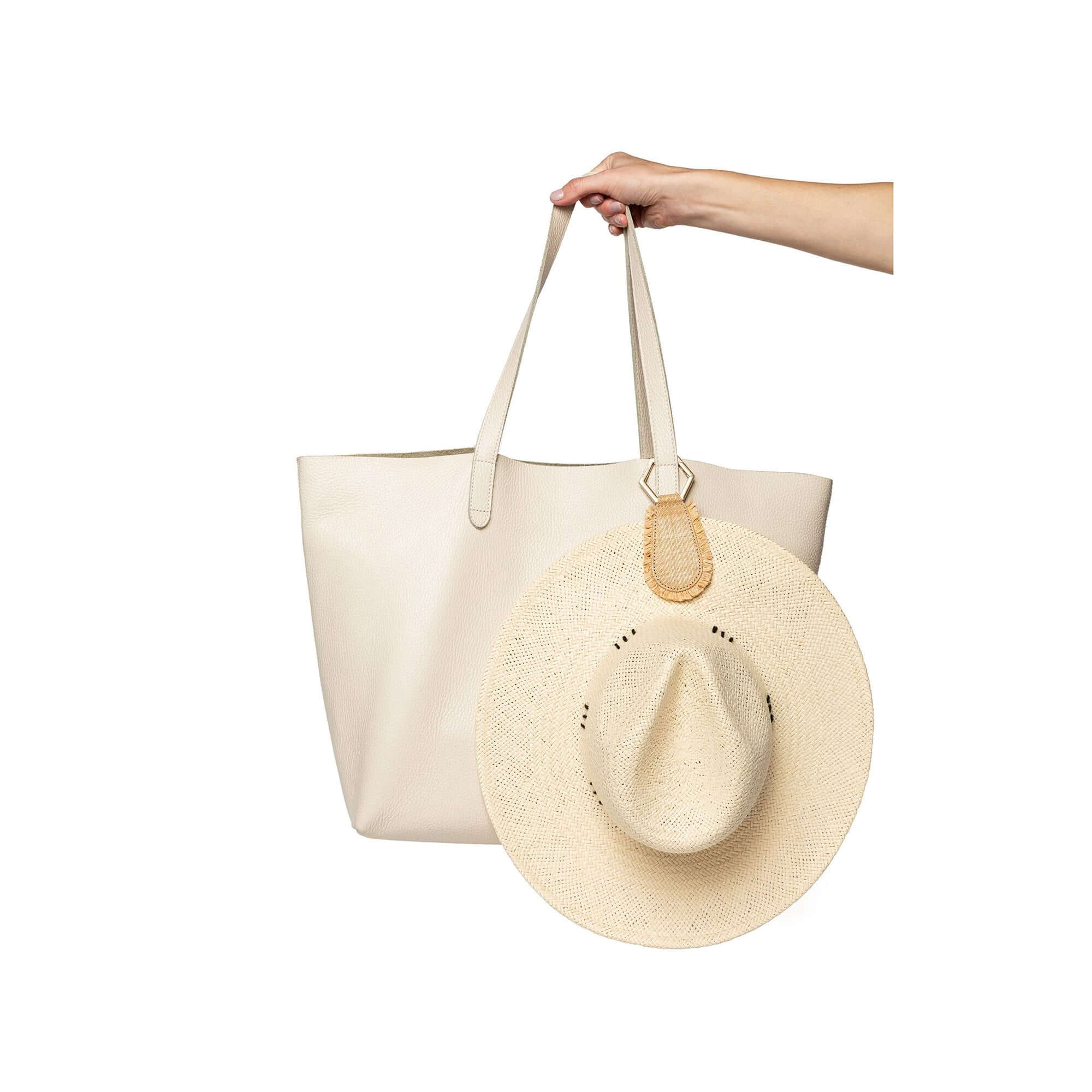 The Fray TOPTOTE Hat Clip with raffia trim holding a hat on a beige tote bag