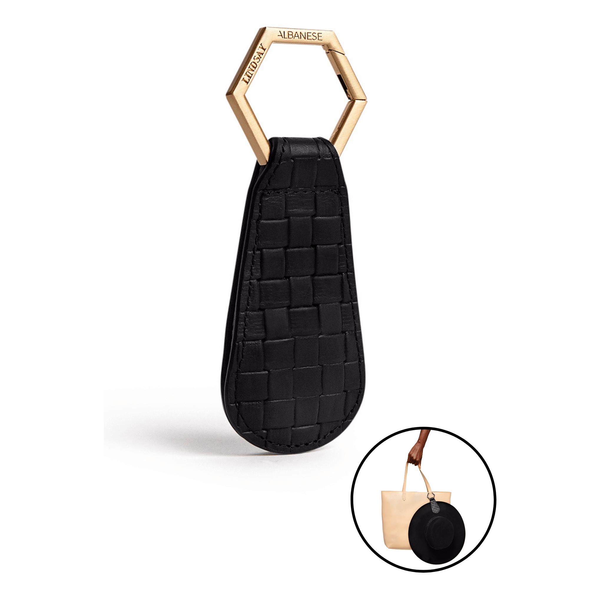 The Drop TOPTOTE Hat Clip in black with gold hexagonal clasp, designed for securely carrying hats hands-free while traveling.