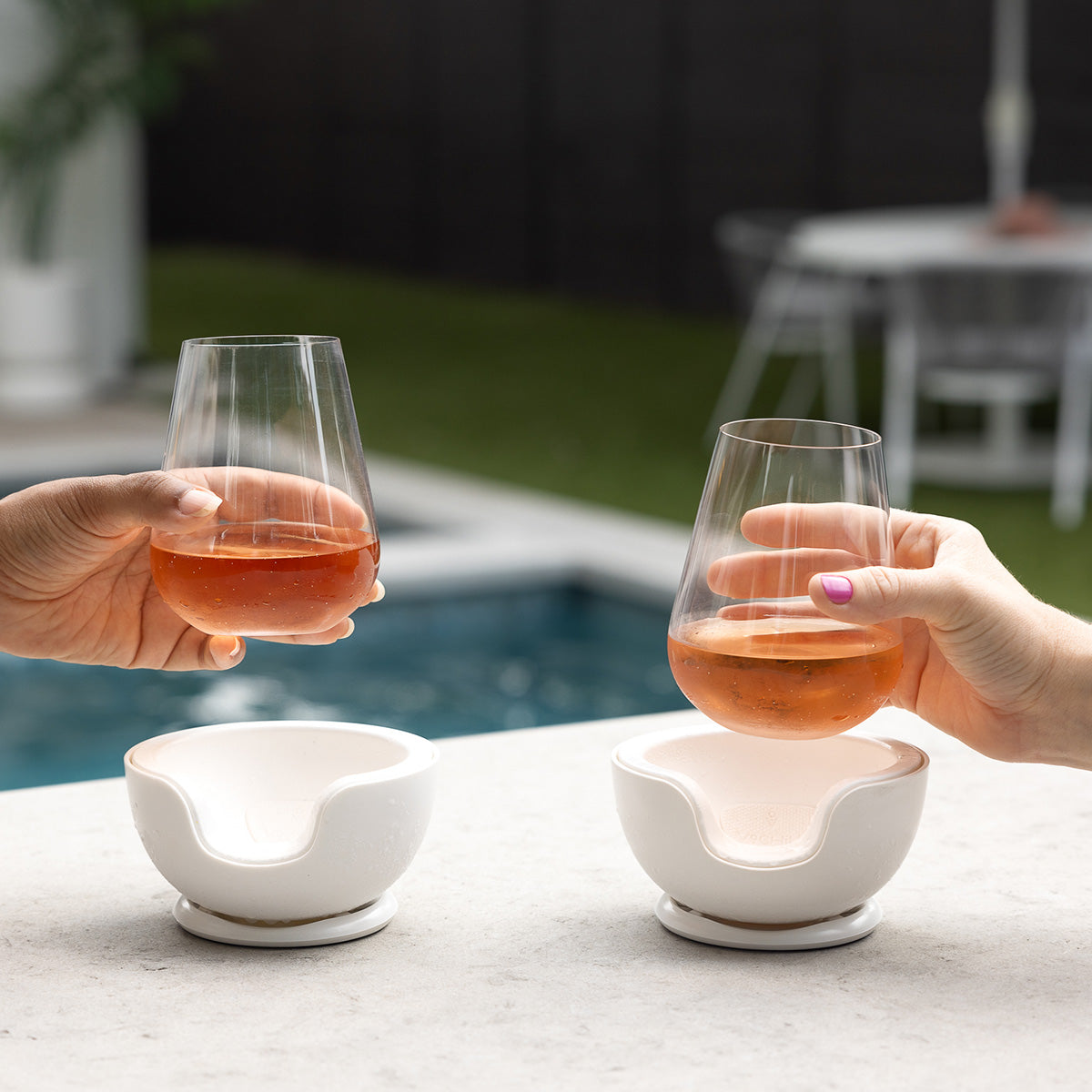 Two stemless wine glasses in VoChill Stemless Wine Chillers by the poolside, keeping wine perfectly chilled.