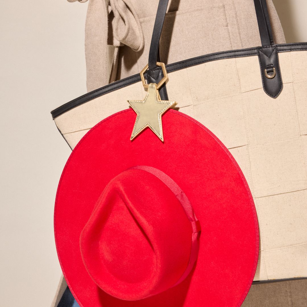 Gold Star TOPTOTE hat clip holding a red hat that is attached to a tan tote bag.