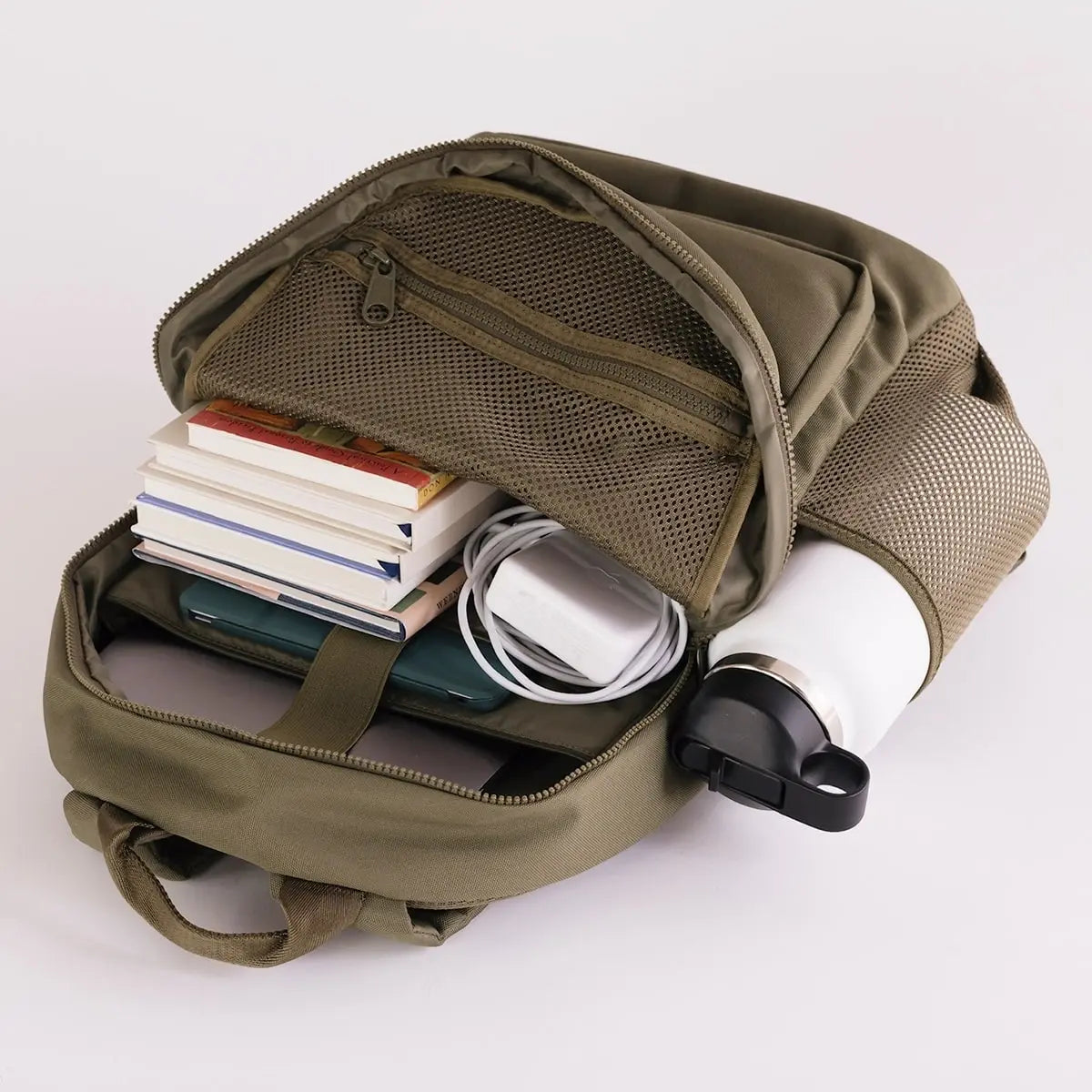August Noa travel backpack in olive. Front view with main pocket open to show storage. 