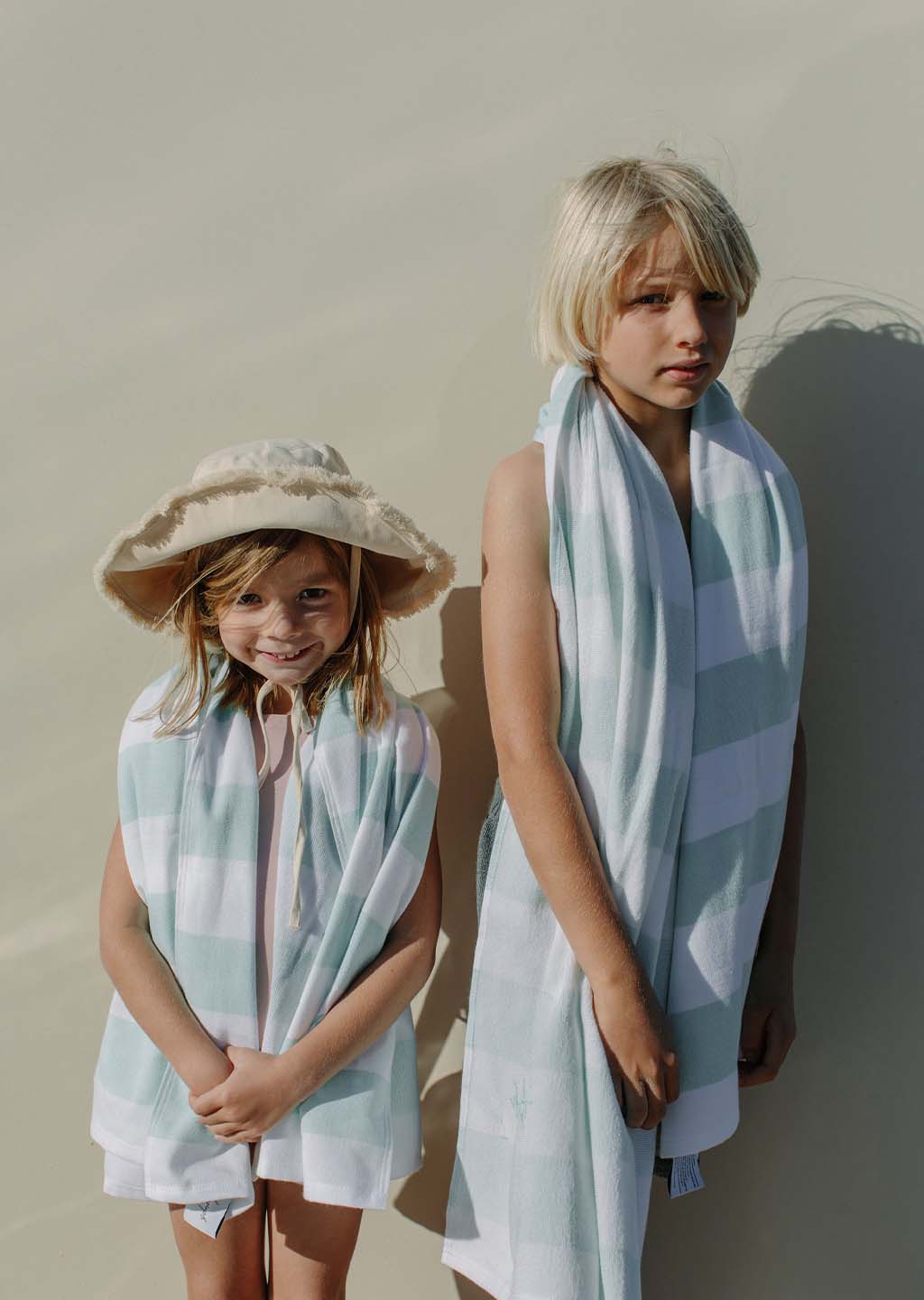The Beach People Kids Reef Green Sand-free Beach towel draped over a boy and girl.