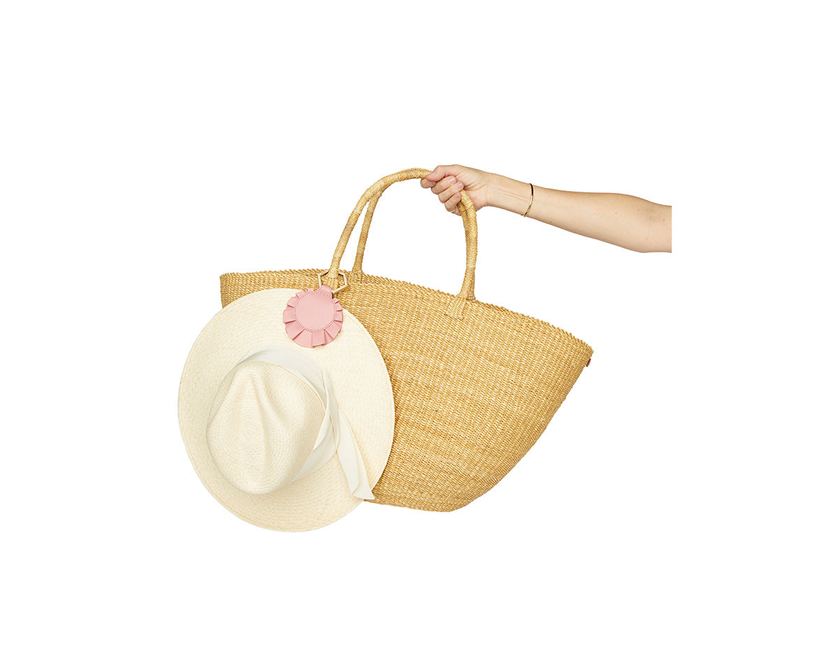 The Femme TOPTOTE attached to a handbag, holding a hat securely with a high-powered magnet closure, showcasing romantic and feminine style features.